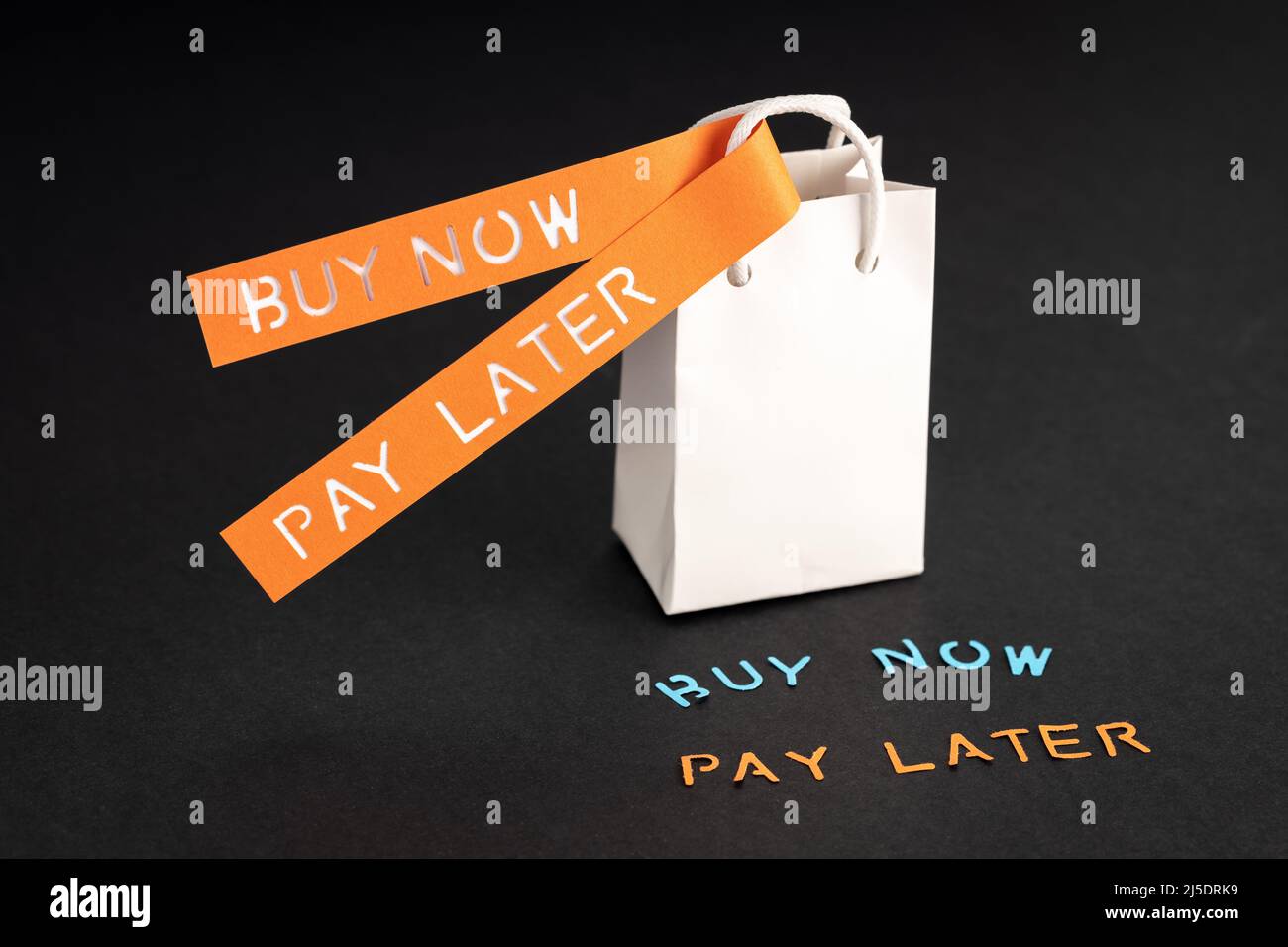 BNPL oder Buy Now Pay Later Concept. Leerer Einkaufstasche und Etiketten mit Meldung auf schwarzem Hintergrund Stockfoto