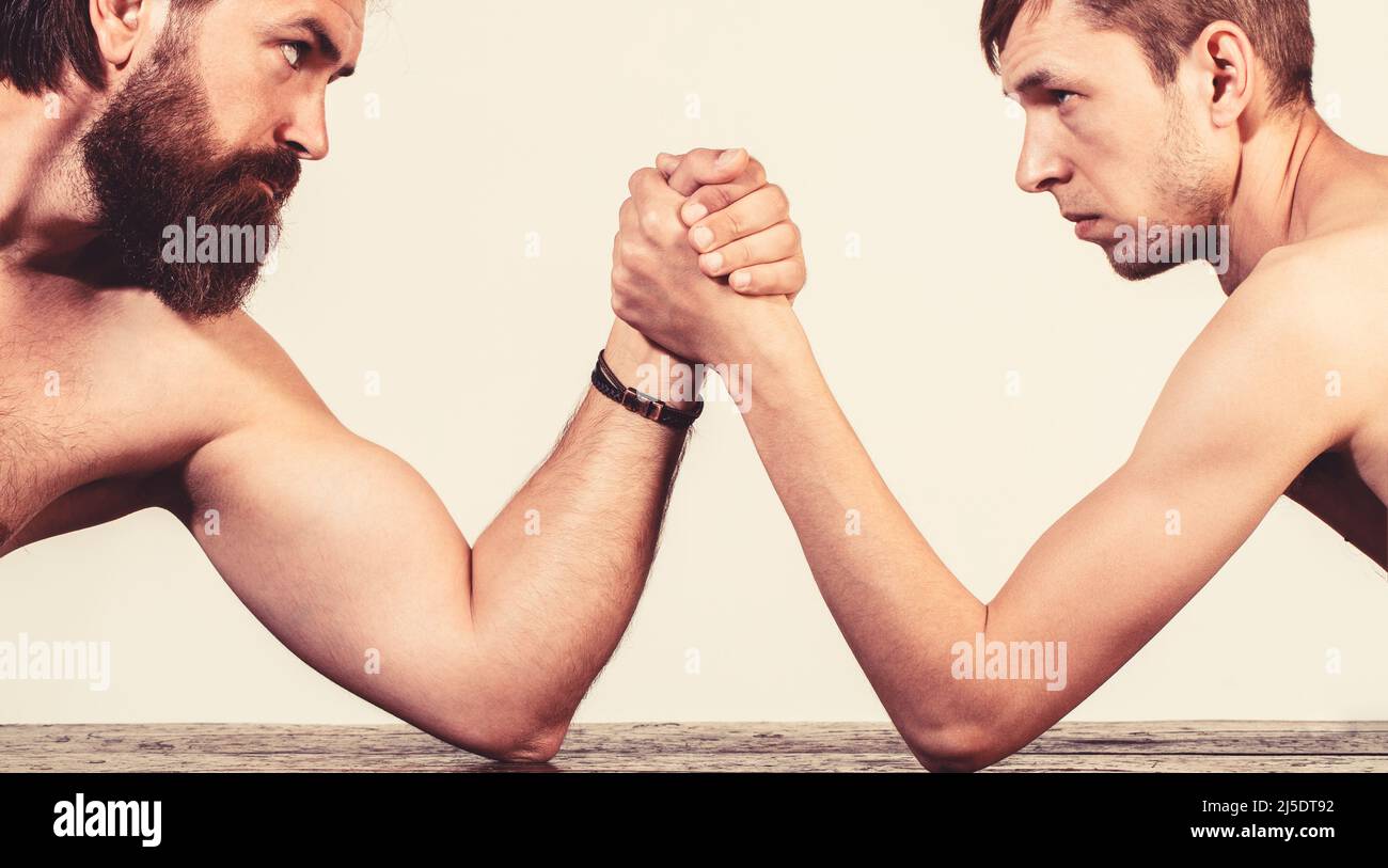 Zwei Männerhände umklammten Arm Wrestling, stark und schwach, ungleiche Übereinstimmung. Stark muskulös bärtigen Mann Arm Ringen ein mickrigen schwachen Mann. Arme ringen dünn Stockfoto