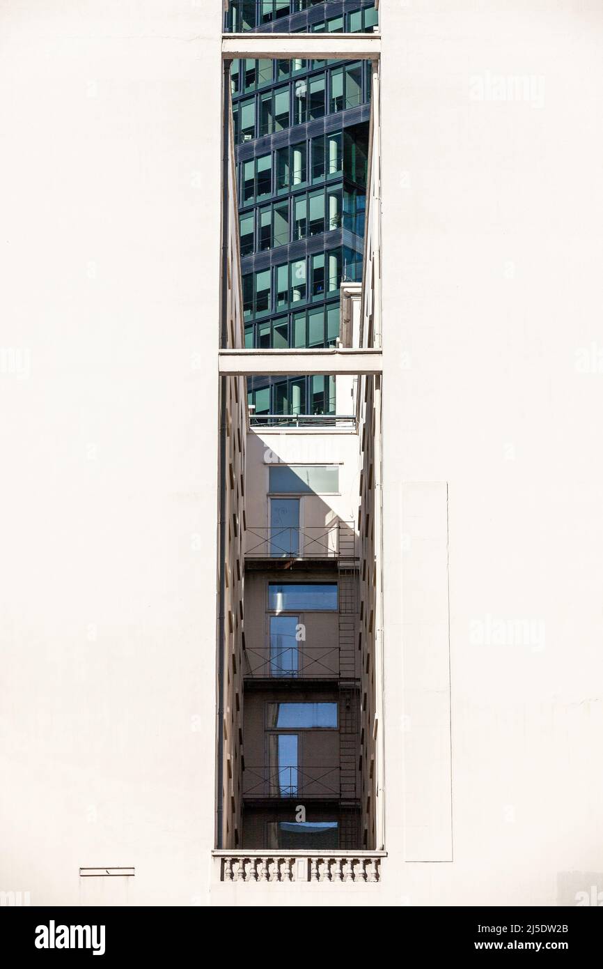 Städtischer Graben. Verglastes Gebäude, das durch zwei blinde weiße Fassaden dicht beieinander gesehen wird. Brüssel. Stockfoto