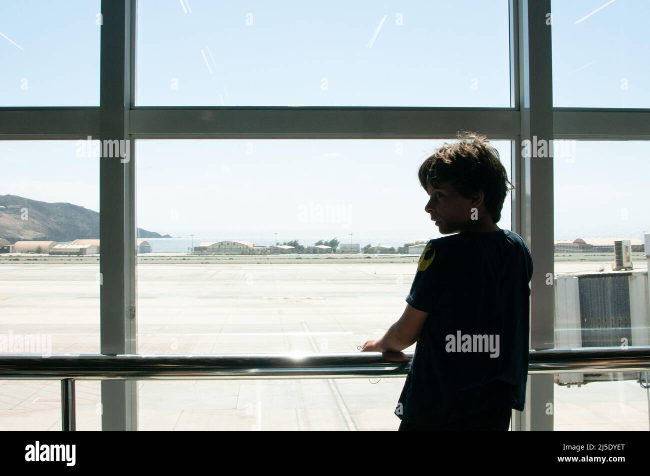 Junge, der aus dem Fenster zum Flughafen schaute Stockfoto
