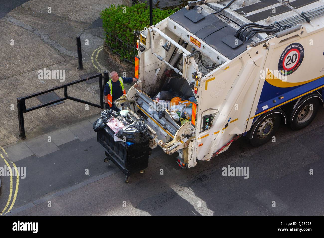 London, UK-17.04.22: Ein Mann, der Müllcontainer in einen Hecklader-Lkw in einer City of Westminster, im Zentrum von London, auslädt Stockfoto