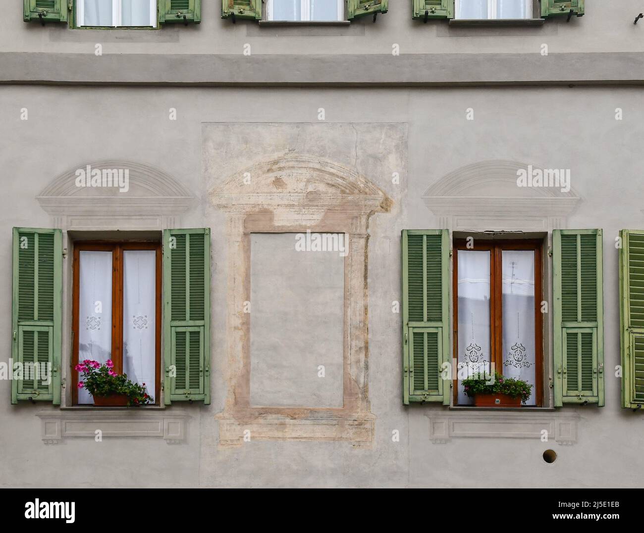 Detail der façade eines alten Gebäudes mit zwei echten Fenstern und einem mit Trompe-l'oeil-Technik bemalten, Sanremo, Imperia, Ligurien Stockfoto