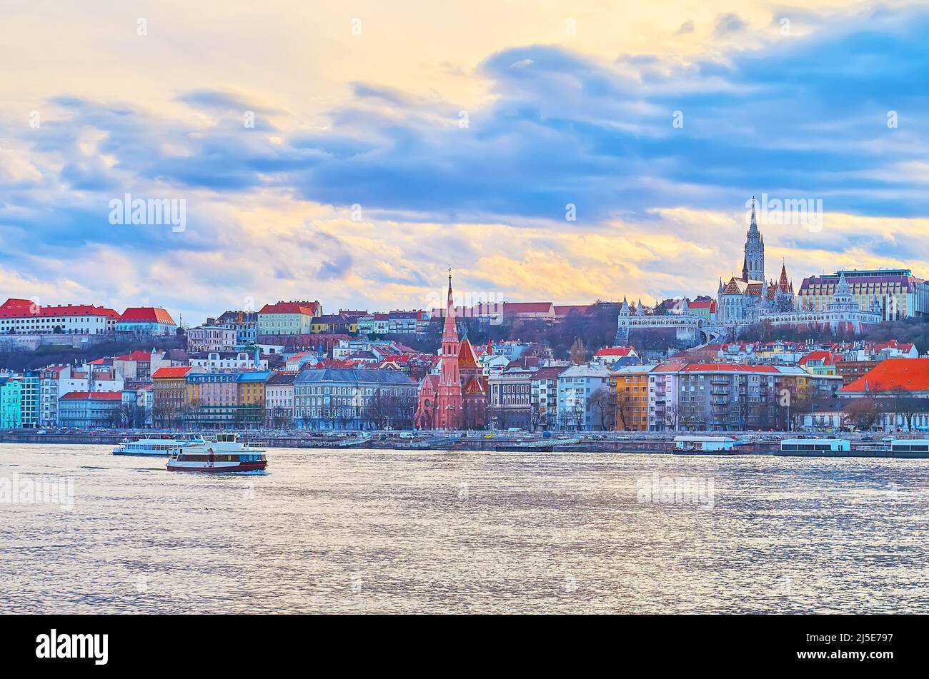 Der farbenfrohe Sonnenuntergang Himmel mit lila Wolken über den Häusern des Budaer Bezirks und der Donau, Budapest, Ungarn Stockfoto