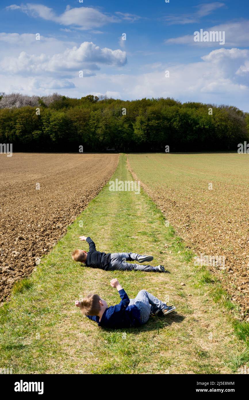 Zwei Jungen Rollen auf dem britischen Land einen Hügel hinunter Stockfoto