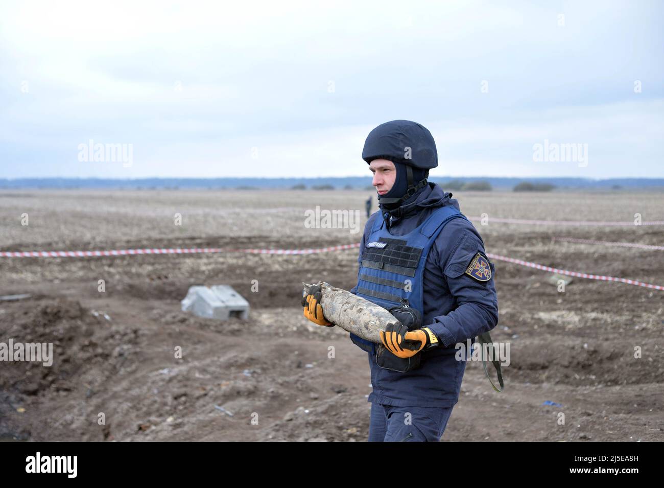 KIEW, UKRAINE - 21. APRIL 2022 - ein EOD-Experte des staatlichen Notdienstes trägt während einer Minenräumungsmission in der Nähe von Bervytsia, A, eine Granate Stockfoto