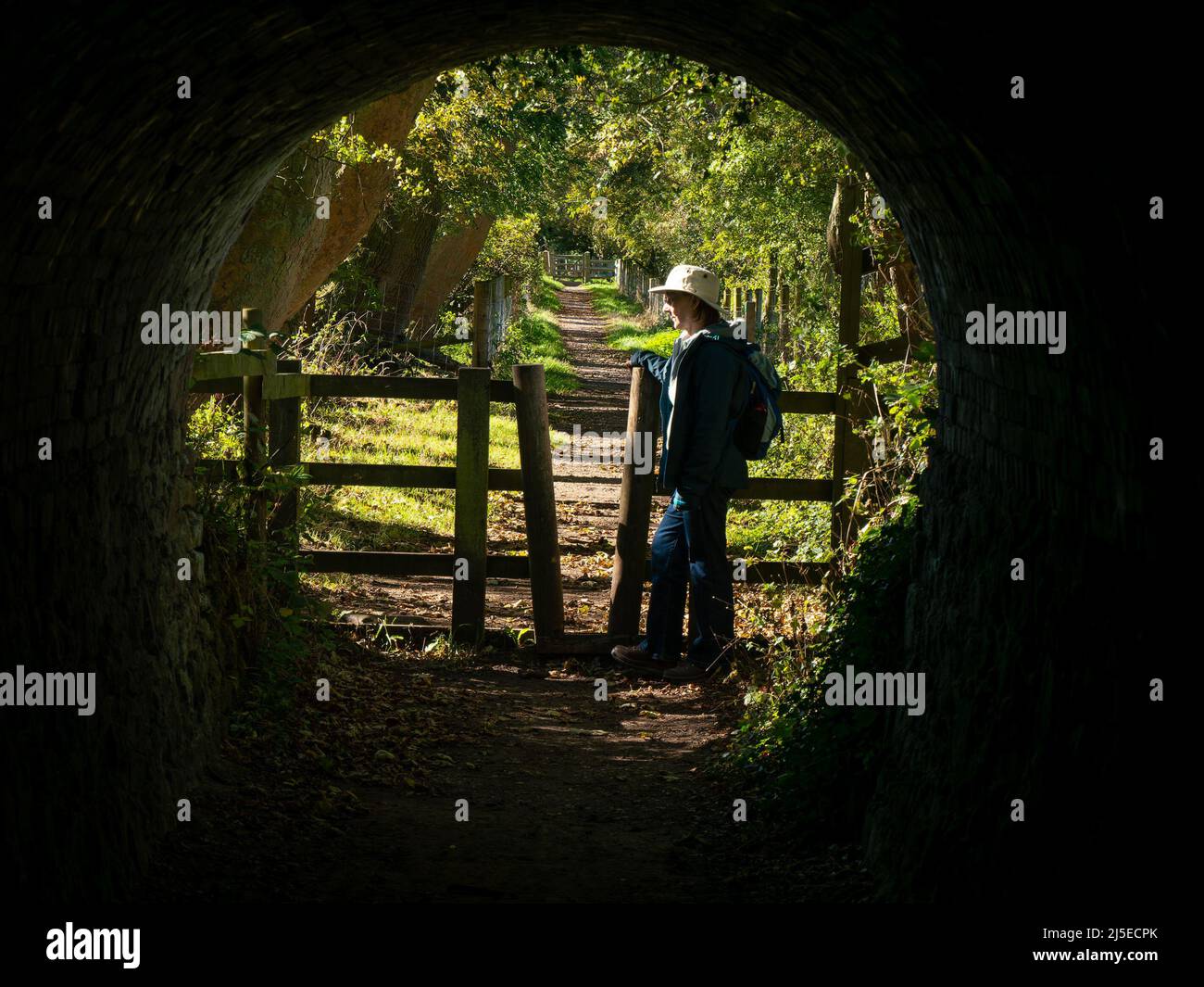 Die Wandererin steht an der Ausfahrt zum Tichnall Limeyards Tramway Tunnel, Derbyshire, England, Großbritannien Stockfoto
