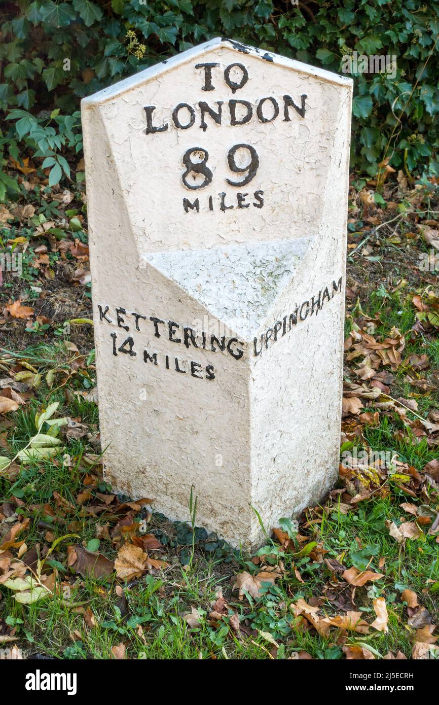 Alte, weiß gestrichene Meilenmarkierung aus Metall am Straßenrand zwischen Kettering und Uppingham am A6003, Rutland, England, Großbritannien Stockfoto