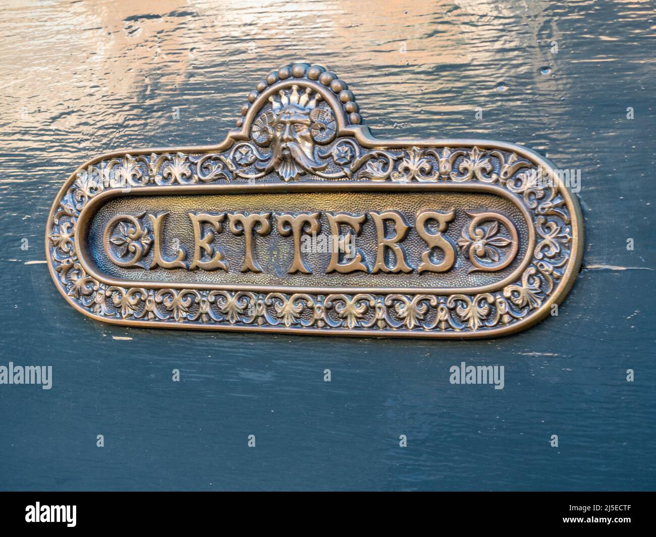 Alte, kunstvoll polierte Messing Briefkasten auf blau / grün bemalte Holz Haustür, UK. Stockfoto