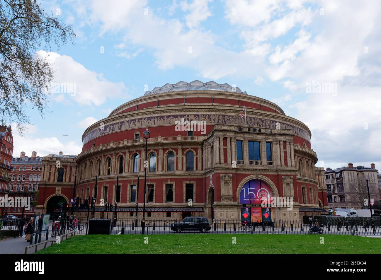 London, Greater London, England, April 13 2022: Taxi und Motorrad passieren die Royal Albert Hall, eine berühmte Konzerthalle in South Kensington. Stockfoto