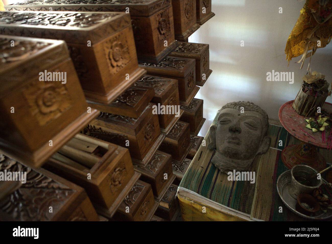 Eine Skulptur, ein Set balinesischer Ausrüstungen und Holzkisten mit alten balinesischen Palmenblättern-Manuskripten im Gedong Kirtya Museum in Singaraja, Buleleng, Bali, Indonesien. „Es gibt nur einen begrenzten Zugang zum Inhalt der Manuskripte, wegen der sprachlichen Schwierigkeiten und der Fragilität des Dokuments“, schrieb ein Team von Wissenschaftlern unter der Leitung von Made Windu Antara Kesiman vom Laboratoire Informatique Image Interaction (L3i) der Universität La Rochelle während der 15. Internationalen Grenzkonferenz in Handschriftenerkennung 2016, Oktober 2016, in Shenzhen, China. Stockfoto