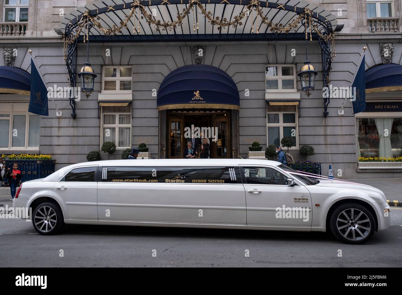 Weiße Stretch-Limousine vor dem Ritz Hotel am 13.. April 2022 in London, Großbritannien. Das Ritz London ist ein denkmalgeschütztes 5-Sterne-Hotel in Piccadilly und ein Symbol für hohe Gesellschaft und Luxus. Es ist eines der renommiertesten und bekanntesten Hotels der Welt. Stockfoto