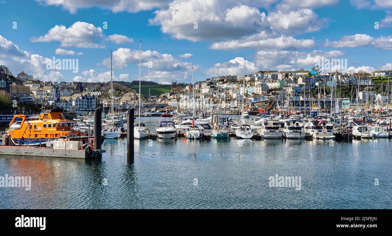 Brixham Marina, mit den schönen farbigen Häusern der Stadt und der Allerheiligen Kirche im Hintergrund und dem Torbay RNLI Rettungsboot im Vordergrund Stockfoto