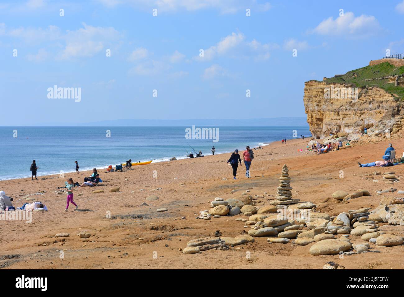 Blick auf den Hive Beach und die Klippen an der Jurassic Coast mit Menschen an einem sonnigen Frühlingstag, Bridport, Dorset, England Stockfoto