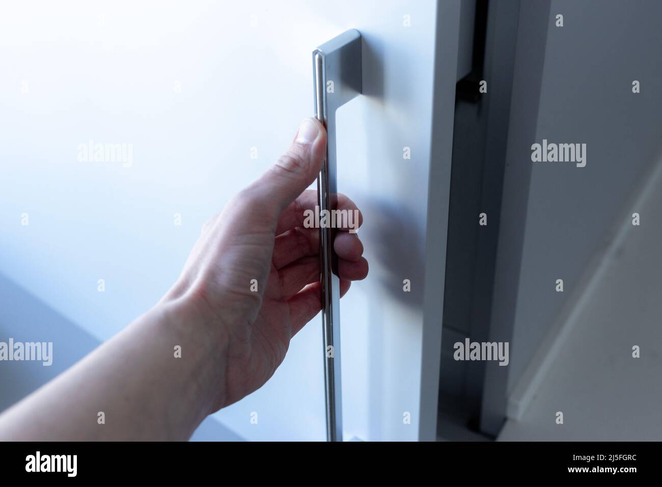 Eine Hand, die eine Schranktür öffnet. Stockfoto