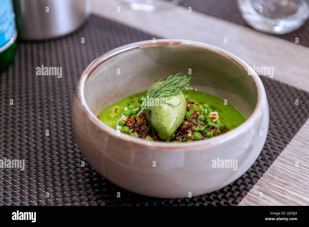Cremesuppe aus grüner Erbse mit Basilikum-Eis. Moderne französische Küche Stockfoto