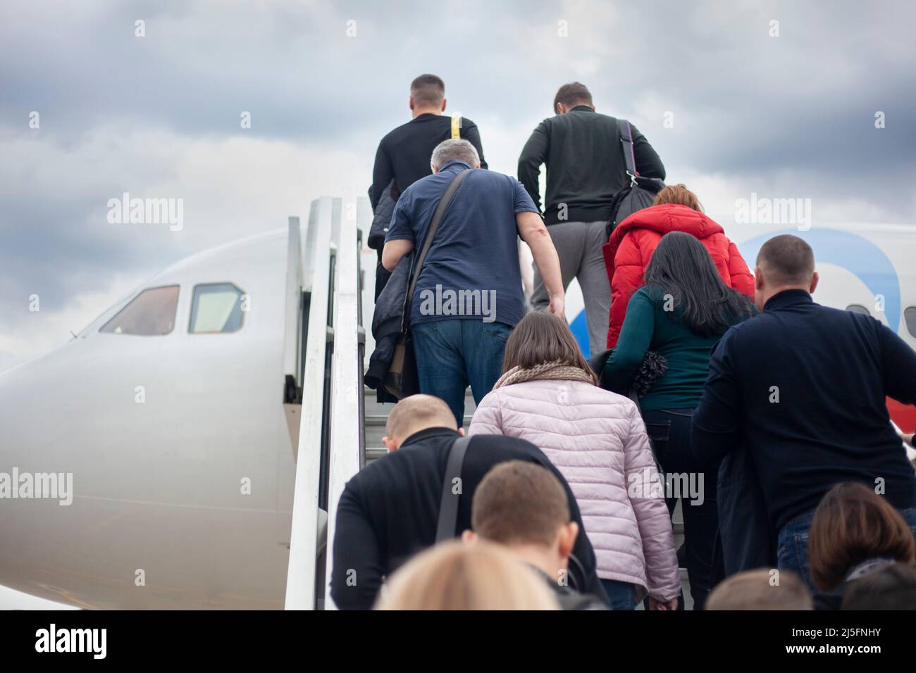 Die Leute klettern die Rampe zum Flugzeug. Passagiere werden in das Flugzeug geladen. Die Leute gehen die Treppe hinauf in die Kabine des Luftverkehrs. Veranstaltung am flughafen Stockfoto