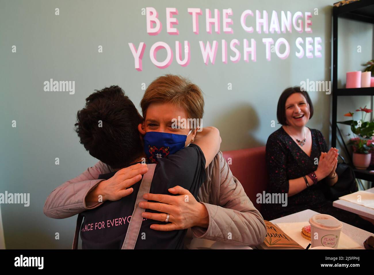 Schottlands erste Ministerin Nicola Sturgeon begrüßt einen Unterstützer im Plant Blonde Cafe in Glasgow, während er sich auf dem Weg zu den wahlen zum rat befindet. Bilddatum: Samstag, 23. April 2022. Stockfoto