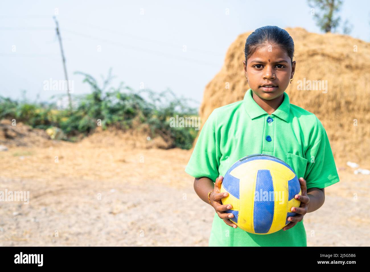 Sweat Village Teenager-Mädchen mit Fußball in der Nähe von Reisfeld nach dem Spielen mit Kopieplatz - Konzept von Urlaub, Hobbys und Aspiration Stockfoto