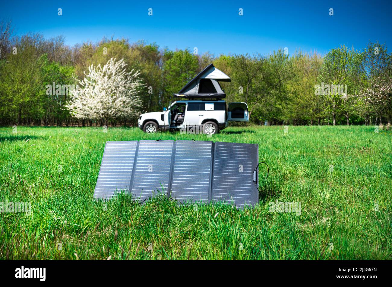4x4 Offroad Fahrzeug Camping mit Dachzelt in einem Meadwow mit Solarpanel zur Energieerzeugung im Vordergrund Stockfoto