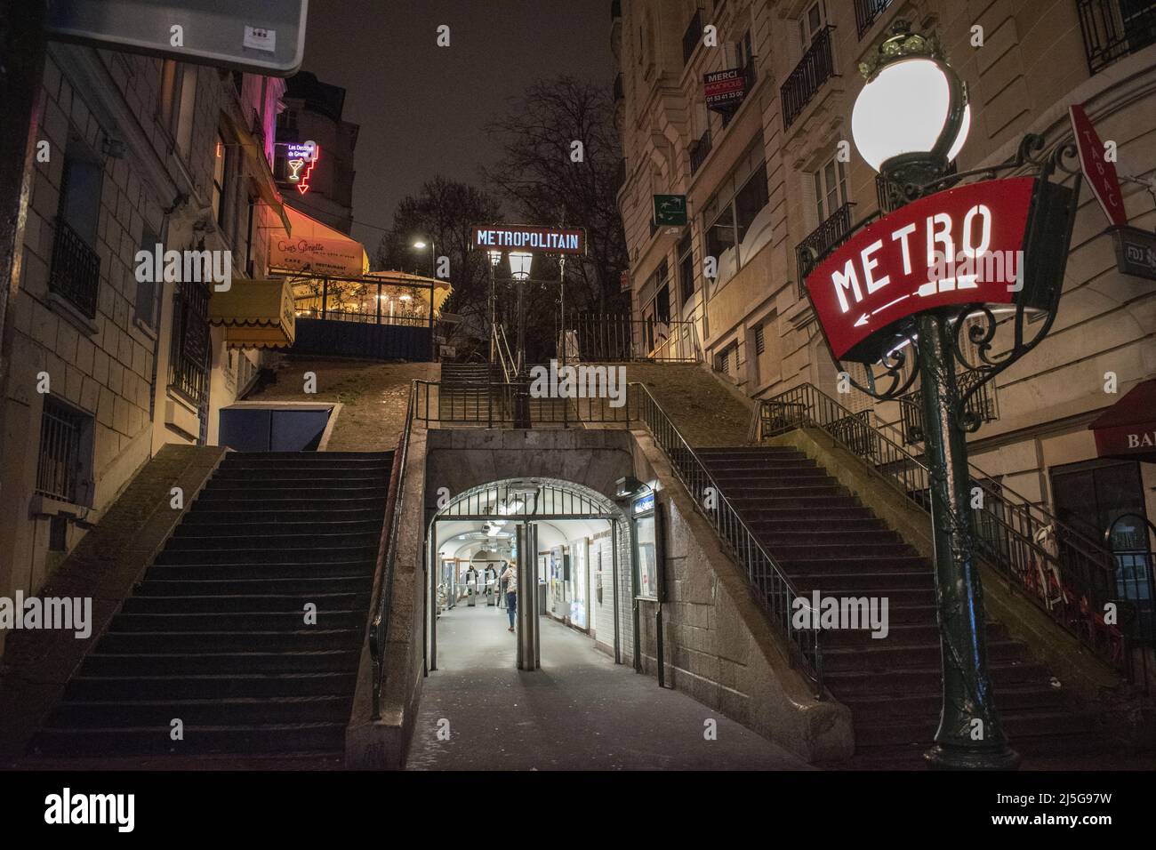 Paris, Frankreich: Nachtansicht, Straßenlaternen und Neonschilder am Eingang der Montmartre Metrostation, berühmter Hügel im nördlichen 18. Arrondissement Stockfoto