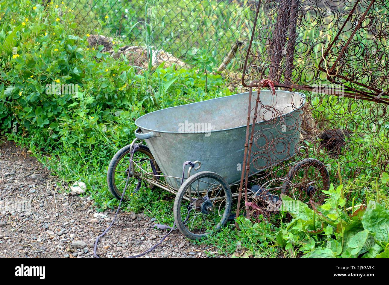 Selbstgemachter Transport für das Gartenkonzept - selbstgemachter Transport für die Datscha und das gusseiserne Gartenbecken auf vier Rädern von einem Kinderwagen mit Seil. Stockfoto