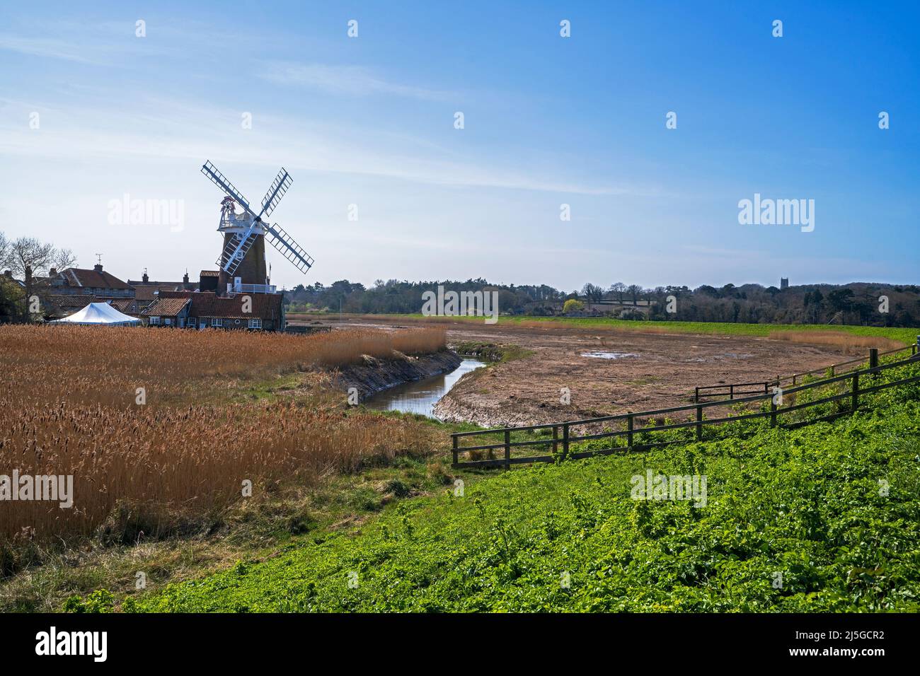 Ein Blick auf die Cley Windmill mit dem Fluss Glaven, der durch Schilfbetten an der Nord-Norfolk-Küste bei Cley-next-the-Sea, Norfolk, England, Großbritannien fließt Stockfoto