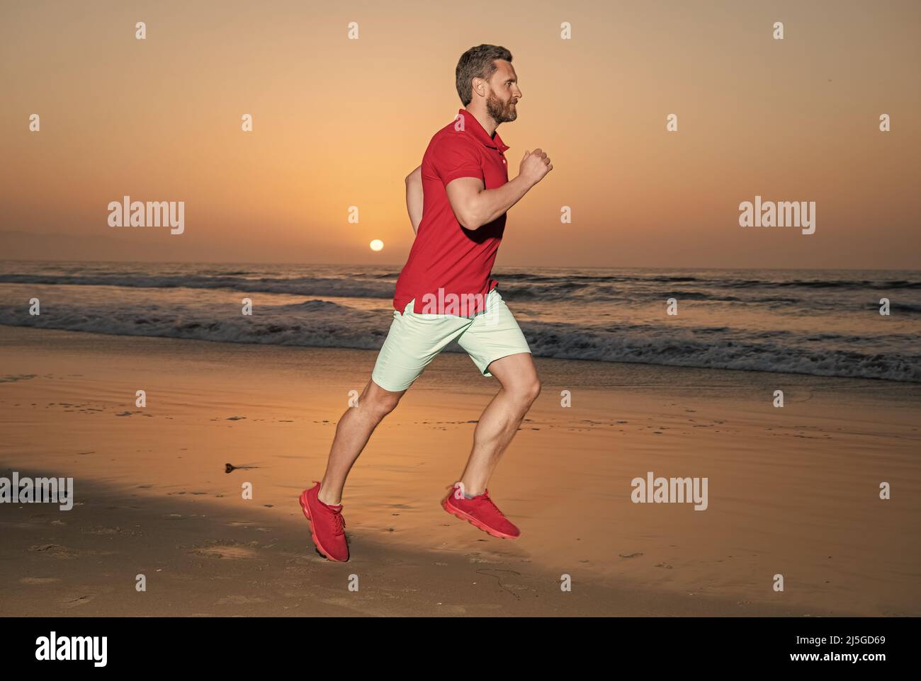 Athlet, Athlet, der am Sommerstrand bei Sonnenuntergang läuft Stockfoto