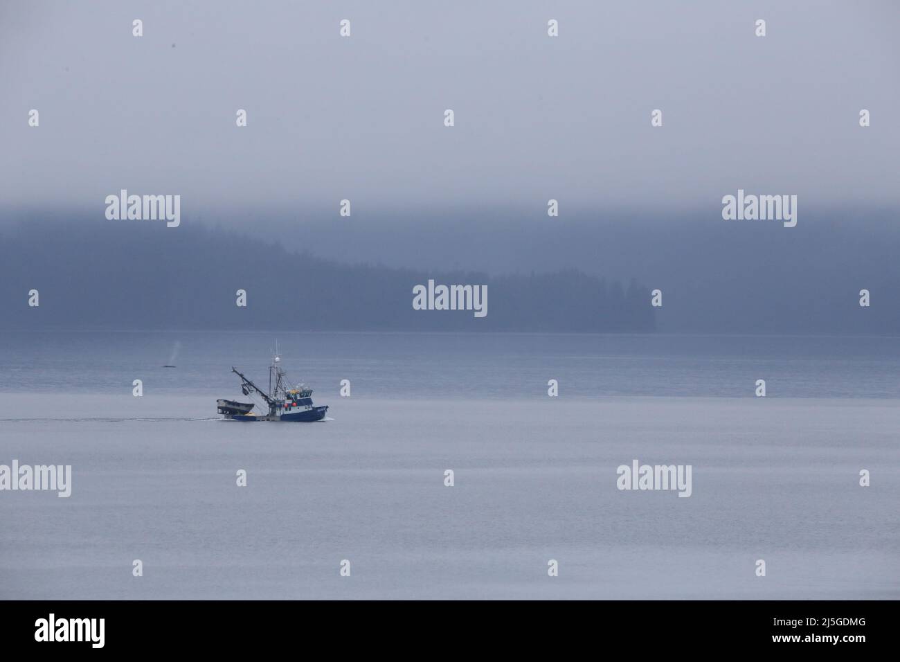 Fischerboot in Alaska mit Wal im Hintergrund Stockfoto