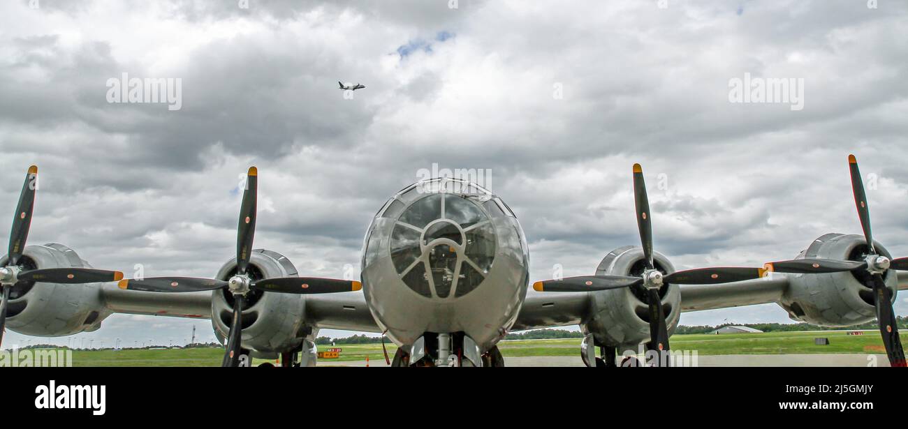 Vorderansicht eines B-29 Super Fortress Bombers aus dem Zweiten Weltkrieg mit einem Verkehrsflugzeug, das im Hintergrund in einem dramatischen Himmel abheben soll. Stockfoto