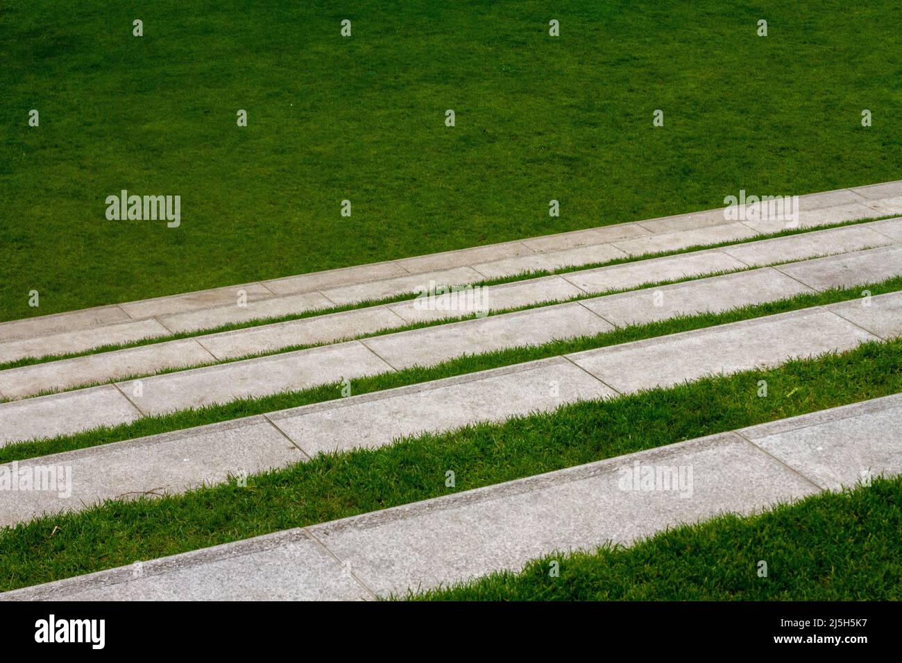 Grüner Rasen mit weißen Treppen als Sitzgelegenheiten für einen Außenbereich Stockfoto
