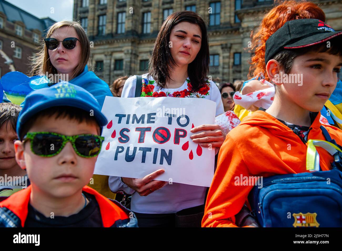 Während der Demonstration wird eine ukrainische Frau mit einem Plakat gegen Putin gesehen. Die ukrainische Gemeinschaft in den Niederlanden, hauptsächlich Frauen und Kinder, versammelte sich im Zentrum der Stadt, um die Aufmerksamkeit der Welt auf die schrecklichen Tragödien der Kinder in der Ukraine zu lenken, die durch die russische Aggression verursacht wurden. Innerhalb von 21 Tagen nach dem Krieg in der Ukraine (Stand: März 16) wurden mindestens 108 Kinder beim Beschuss der russischen Streitkräfte getötet und mehr als 100 verletzt. Während des Protestes hielten einige der Frauen Puppen in einer weißen Decke mit gefälschten Blutflecken. Stockfoto