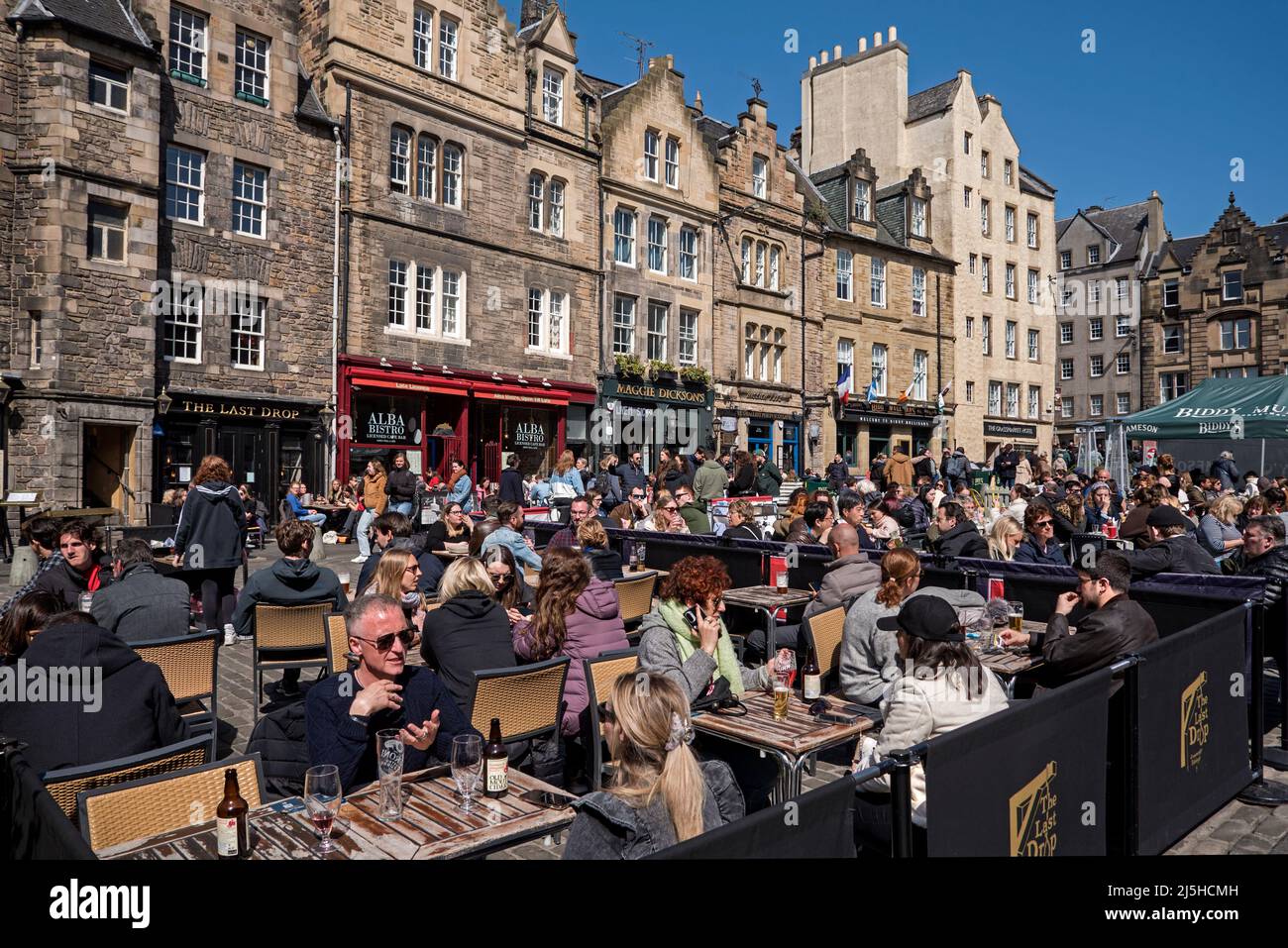 Touristen und Einheimische entspannen sich im Freien und genießen die Frühlingssonne im Grassmarket, Edinburgh, Schottland, Großbritannien. April 2022. Stockfoto