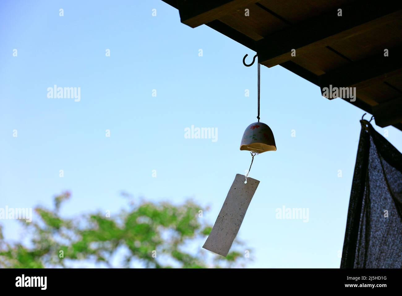 Der Dachvorsprung eines Ladens, in dem ein Windspiel namens „Furin“, eine japanische Sommertradition, aufgehängt wird. Stockfoto