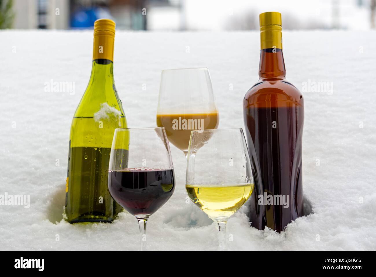 Flaschen Wein und Cremespirituose im kalten Schnee Stockfoto