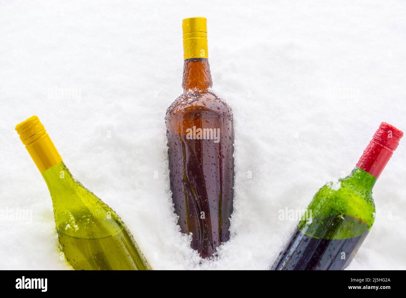 Flaschen Wein und Cremespirituose im kalten Schnee Stockfoto