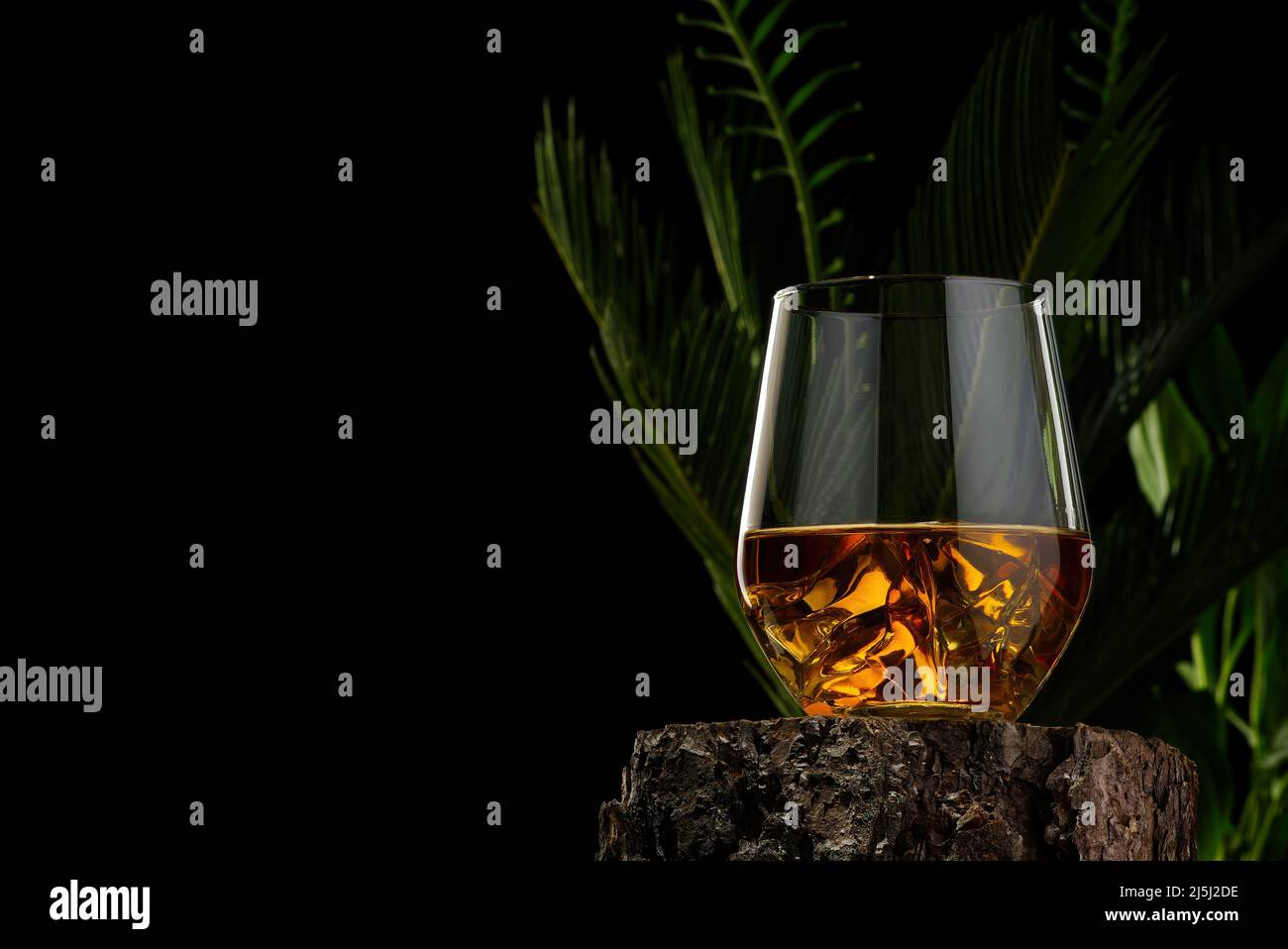 Wisky Glas auf Holzbalken auf schwarzem Hintergrund. Wisky Glas ohne Eis Stockfoto