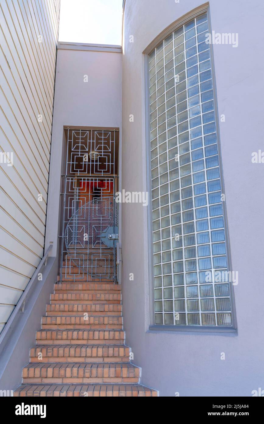 Eine Treppe mit Ziegelsteinen führt zu einem schmiedeeisernen Eingangstor in San Francisco, Kalifornien. Haus außen mit Treppe in der Mitte der beigen Wand auf der l Stockfoto