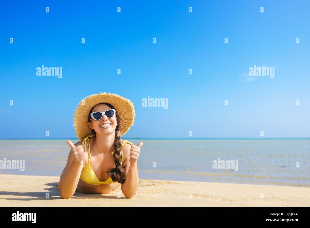 Glückliche Frau in Strohhut und Sonnenbrille am Sandstrand Stockfoto