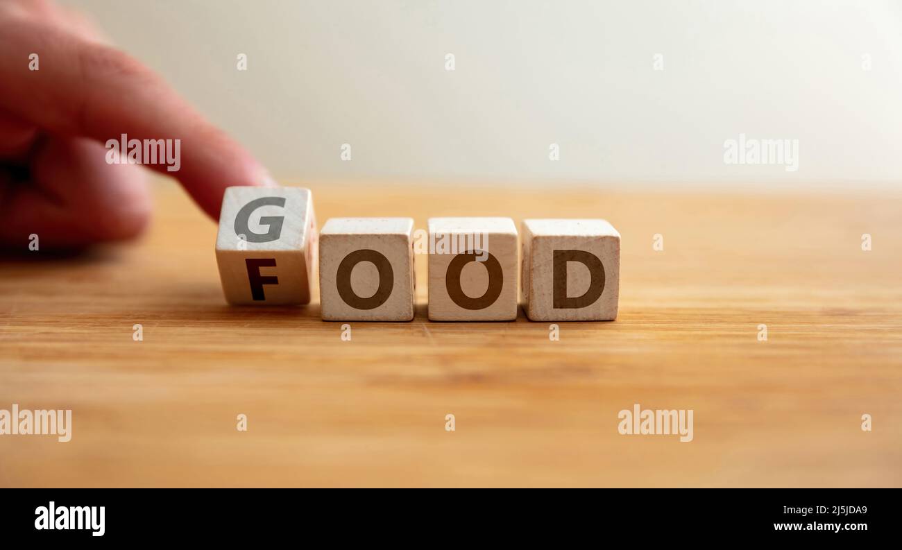 Gutes Essenskonzept. Die Hand dreht den Buchstaben auf dem Holzwürfel und ändert das Wort „Essen“ zu „gut“. Botschaft für gesunde Ernährung, Fitness, Lifestyle, Kraftkörper. Stockfoto