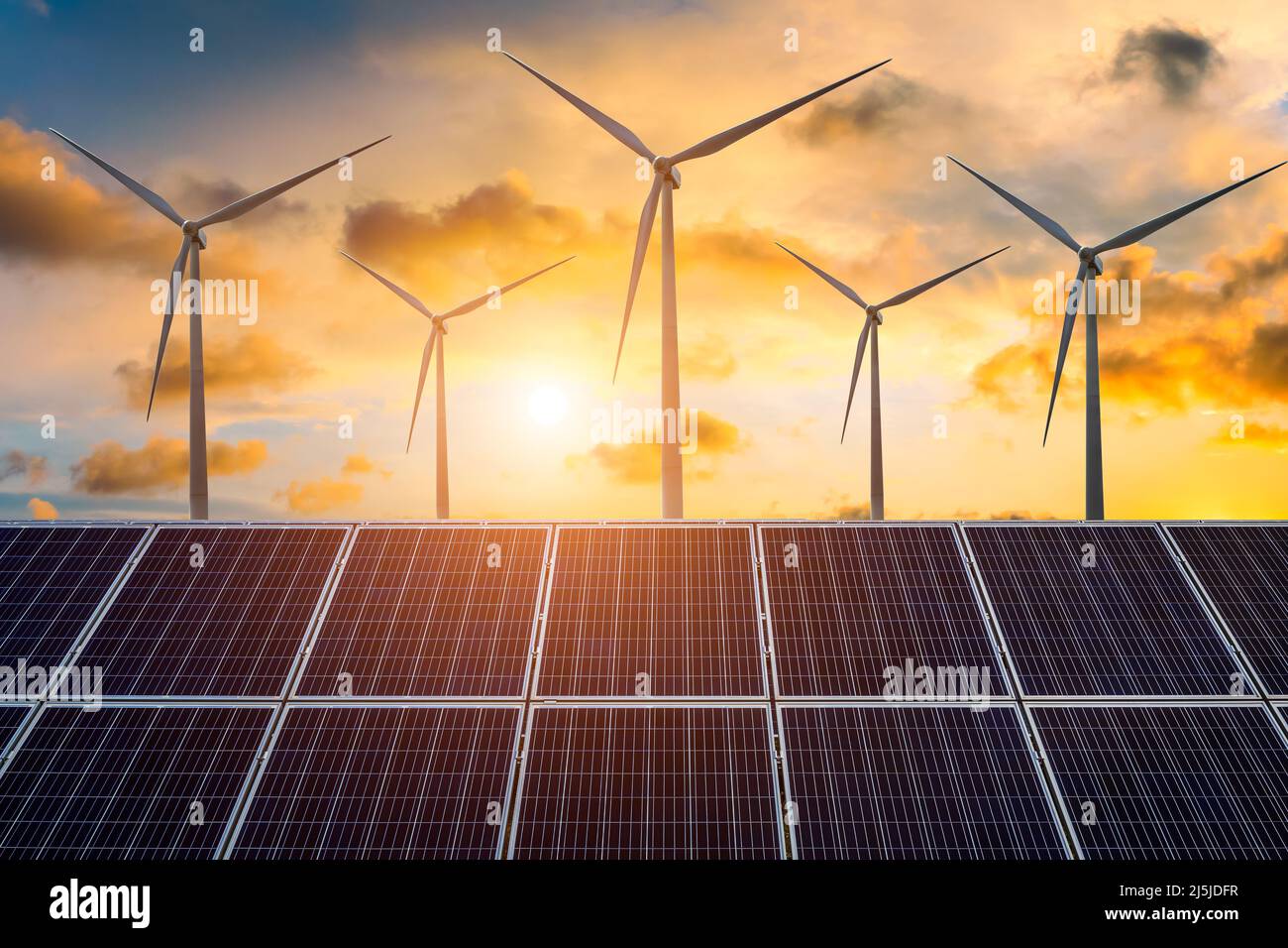 Windturbinen und Sonnenkollektoren bei Sonnenuntergang. Konzept der erneuerbaren Energien. Stockfoto