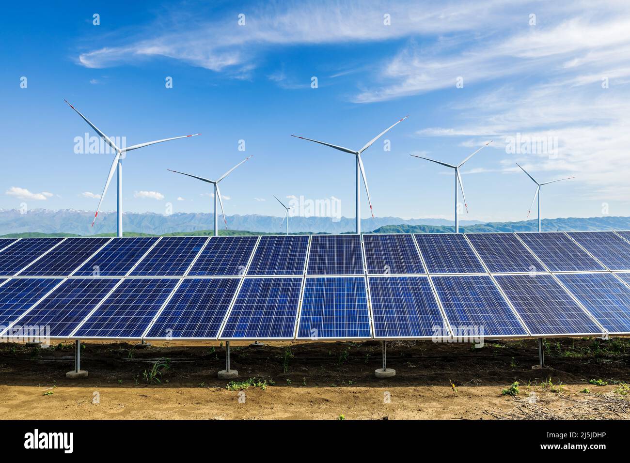 Sonnenkollektoren und Windkraftanlagen mit Berglandschaft unter blauem Himmel. Konzept für grüne Energie. Stockfoto