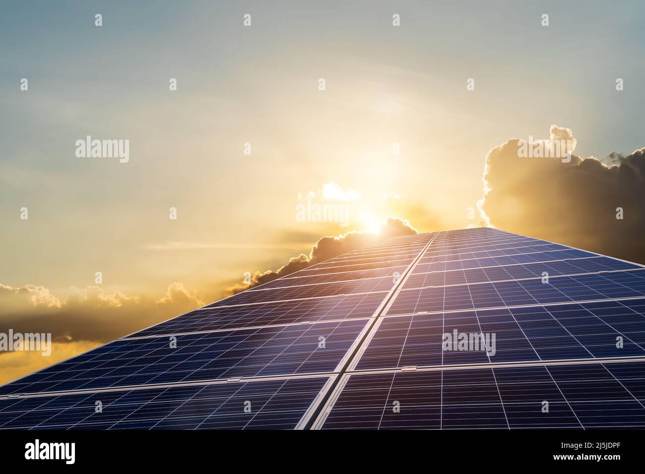 Sonnenkollektoren und wunderschöne Sonnenuntergangswolken. Konzept der grünen Energie. Stockfoto