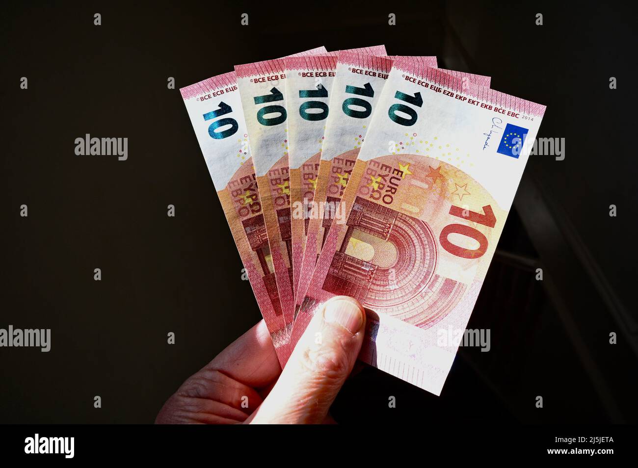 Nahaufnahme eines hochrangigen Mannes, der zehn Euro-Scheine hält Stockfoto
