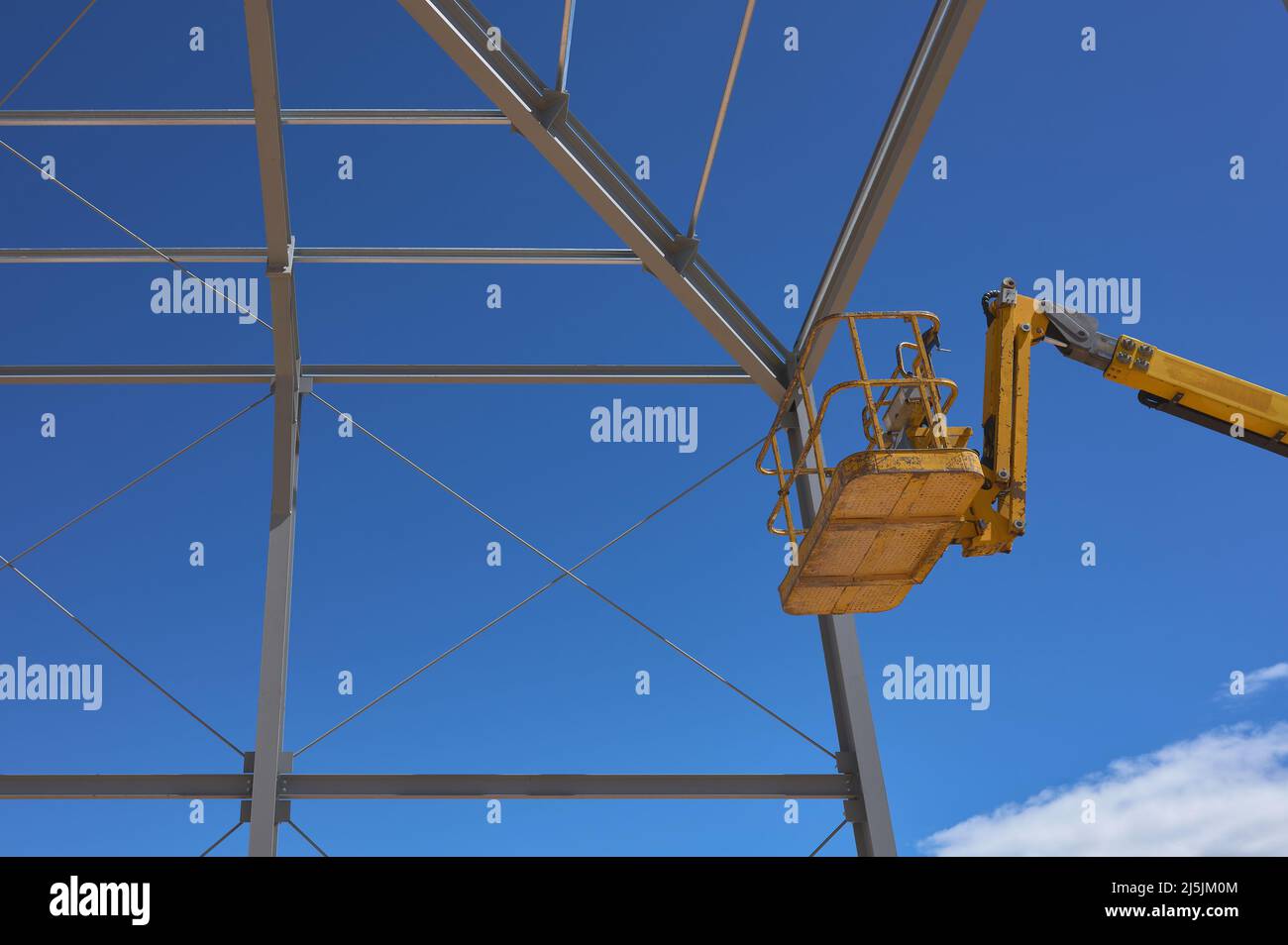Detail einer gelben Hebebühne für den Bau einer Metallkonstruktion Stockfoto