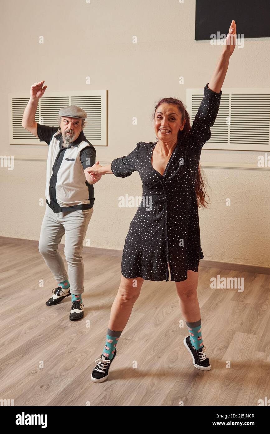 Ein Paar mit älteren Erwachsenen, das lindy Hop in einem Ballsaal tanzt Stockfoto