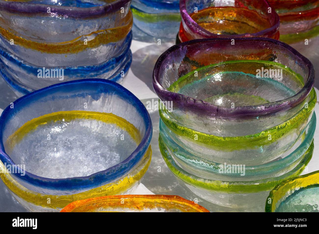 Bunte Glasschalen auf einer weißen Oberfläche schaffen einen abstrakten Hintergrund. Stockfoto