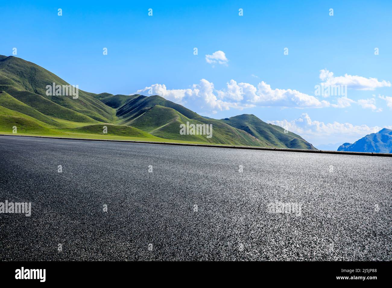Leere Asphaltstraße und grüner Berg unter blauem Himmel Stockfoto