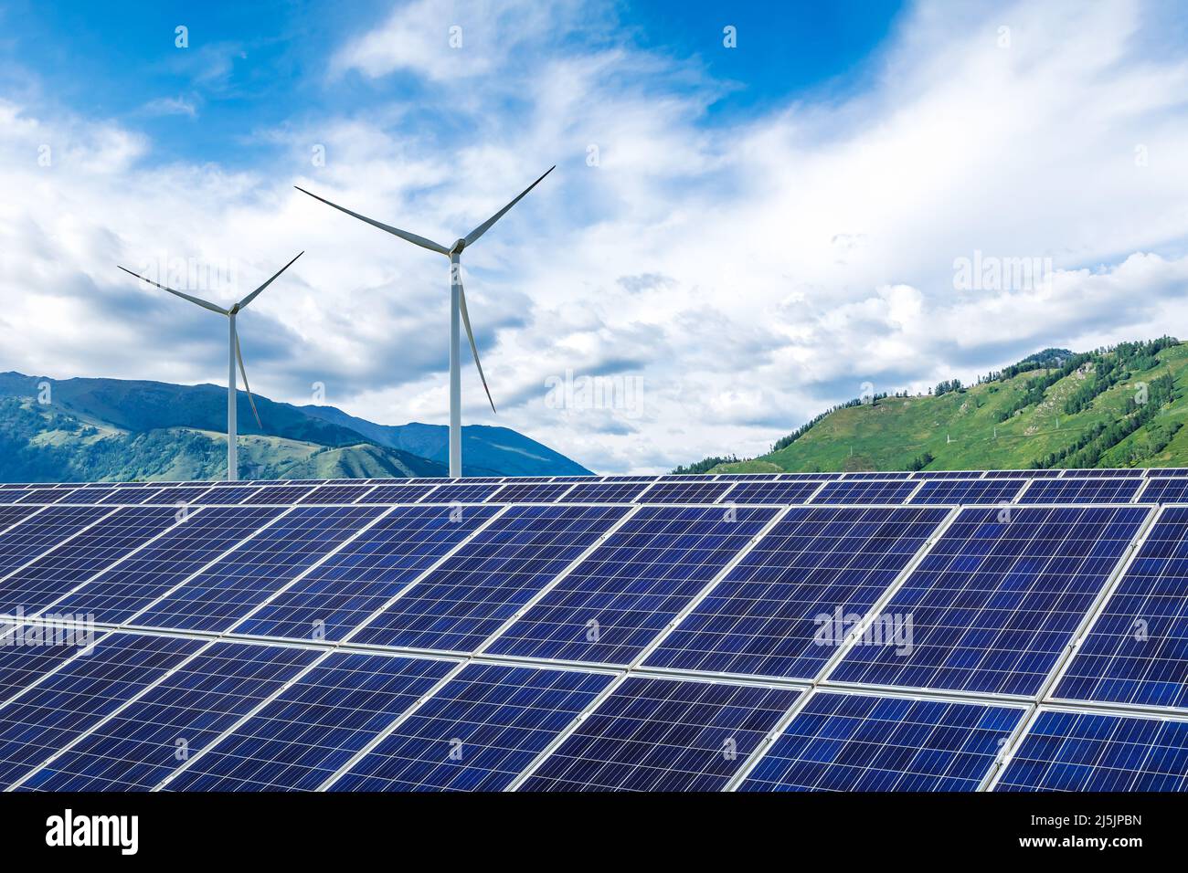 Sonnenkollektoren und Windkraftanlagen mit Berglandschaft unter blauem Himmel. Konzept für grüne Energie. Stockfoto