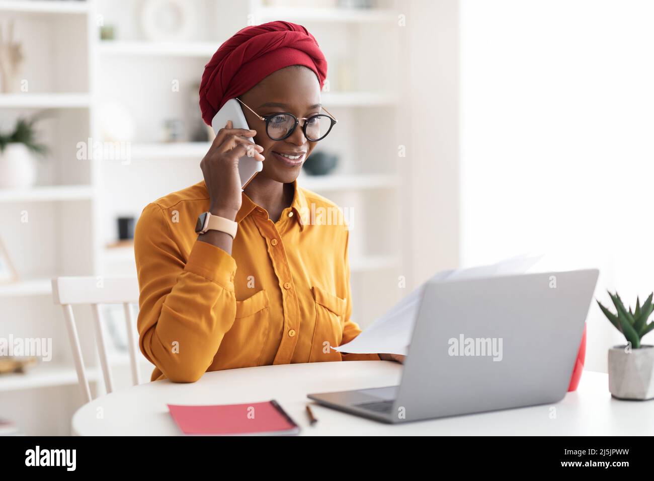Stilvolle afroamerikanische Frau im Turban, die von zu Hause aus arbeitet Stockfoto