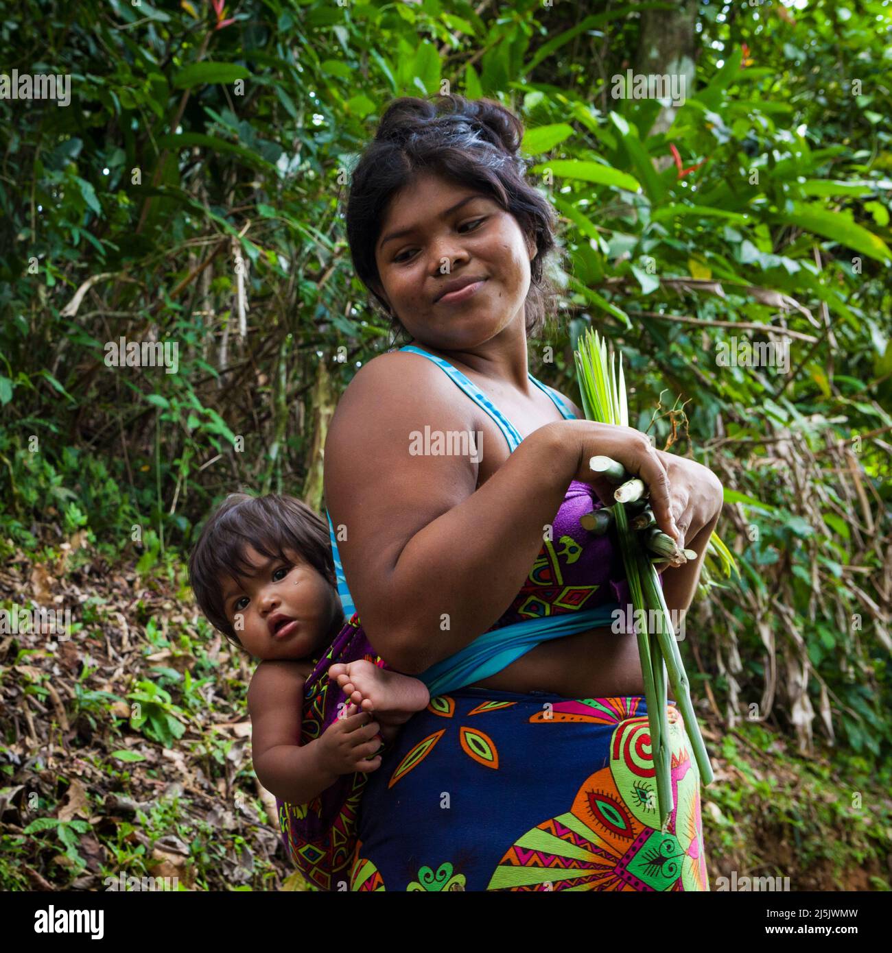 Embera inderin und Baby mit Ernte im Regenwald in der Nähe des Dorfes neben Rio Pequeni, Provinz Colon, Republik Panama, Mittelamerika. Stockfoto